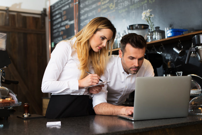 Restaurant owners using apps with laptop