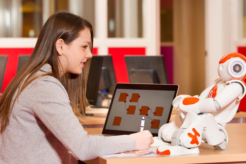 Teen learning with humanoid robot at school